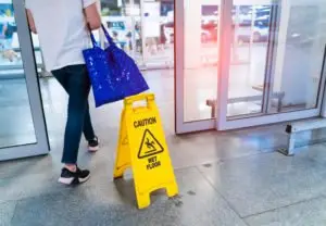 A woman walking past a wet floor sign.