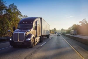 A black big rig truck on a highway.