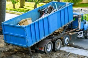 A blue truck loading a garbage container.