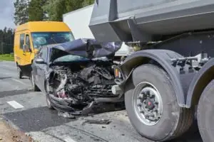 A car that’s been damaged after a collision with a truck and van.