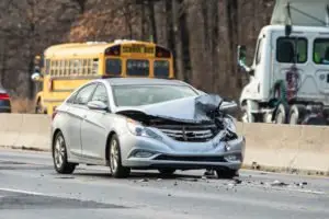 A damaged silver car on a highway.