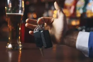 guy holding car key near a beer