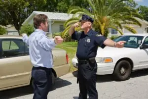 A police officer performing a field sobriety test with a man.