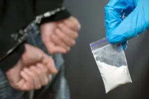 person holding cocaine bag while other in handcuffs