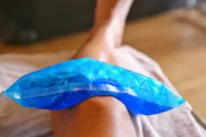 person using a cold pack on a knee injury