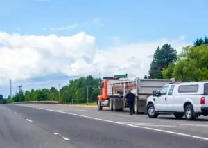 A police officer walking up to the driver of a construction truck.