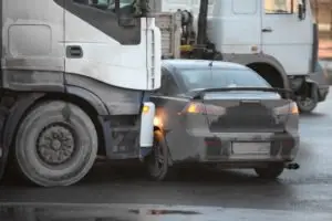 A truck colliding with the side of a black car.