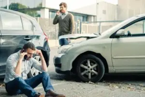 Two men on phones near a car accident.