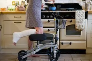 woman doing dishes with leg in a cast