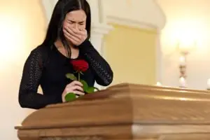 A woman in black, crying in front of a casket.