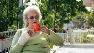 A woman with a bandaged hand drinking from a coffee mug.