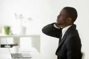 black man with neck pain at his desk