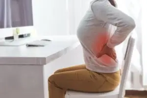 woman sitting at a desk with back pain