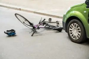 green car with bicycle accident