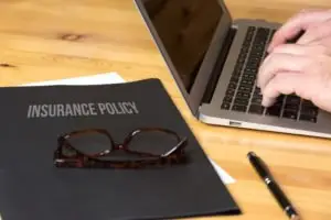 person on computer next to insurance paperwork
