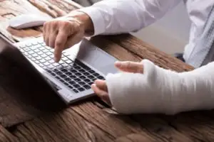 person typing with an arm cast