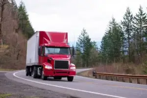 big rig truck comes around a bend in the road