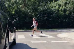 child crosses the street while traffic waits