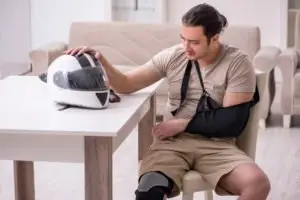injured man rests a hand on his motorcycle helmet