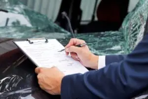 insurance adjuster reviews vehicle damage after crash