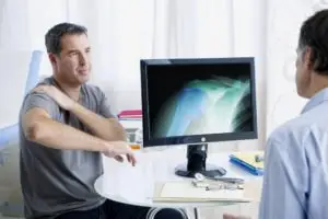 patient with injured shoulder discusses treatment with doctor