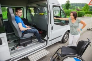 boy in a wheelchair is picked up for school