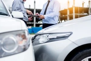 insurance agent taking notes while examining vehicle damage