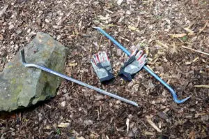 Crowbars and gloves laying on the ground.
