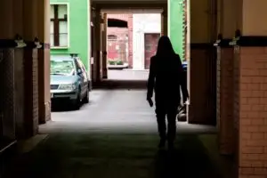 woman walking through dark tunnel to parking lot