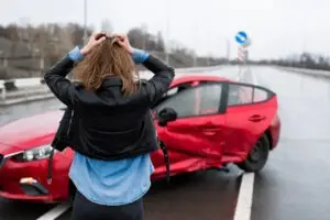 woman surveying damage to red car