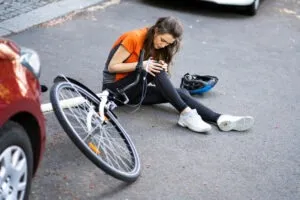 woman nursing knee after bike crash