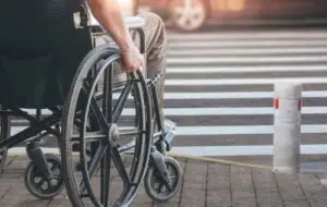 person in wheelchair waiting to enter crosswalk