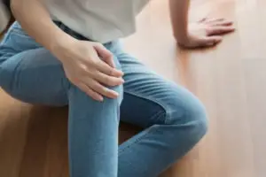 Injured-woman-grabs-knee-on-floor