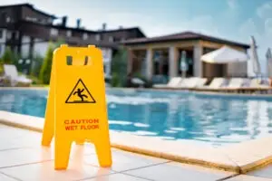 A wet floor sign has been placed in a swimming pool area. Contact a Naples premises liability lawyer.