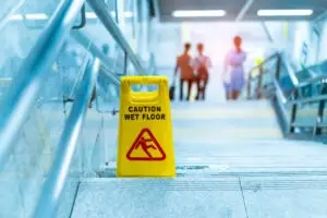 A wet floor sign is placed on stairs. Hire a Sanibel premises liability lawyer now.