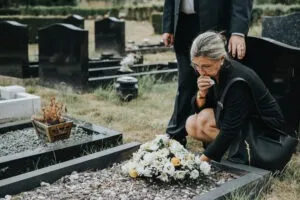 A woman lays flowers at a grave. A wrongful death lawsuit attorney can help Alva, FL, parties sue for losses in a negligence accident.