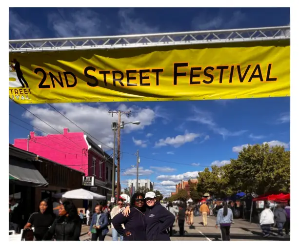 Second Street Festival 2023: A colorful crowd enjoying music, art, food, and community spirit in Richmond's Jackson Ward. Attorney Holly Ortiz and Attorney Porscha Brown are featured under the 2nd Street Festival Banner smiling.