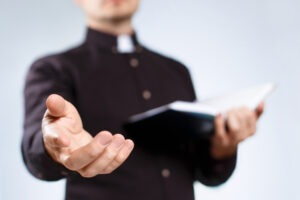 A clergy member holding out their hand. What is the average settlement for clergy abuse?