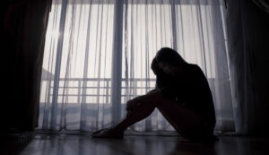 Sad-woman-sitting-on-the floor-by-the-window