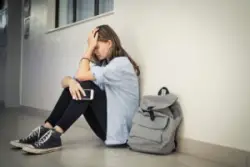 college-student-sits-on-floor-depressed