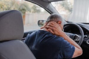 Man grabs his neck in pain after a car accident whiplash.