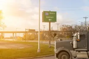 gray truck drives toward detroit sign
