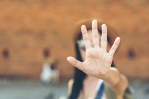 woman holds hand in front of face to show stop sexual assau