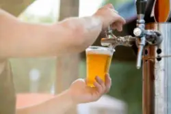 beer poured into glass from a tap by a bartender