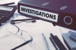 ring binder of investigations on desk near report