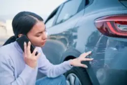 woman inspecting scratched car