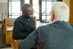 black priest talking with white parishioner