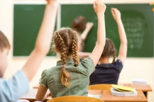 kids in a classroom raising their hands