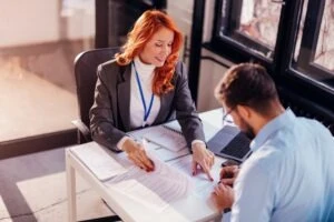 redhead lawyer showing client where to sign