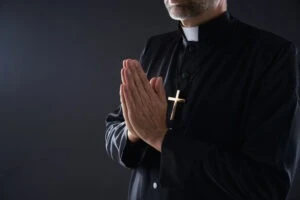 a priest praying. How long does it take to settle a clergy abuse case?